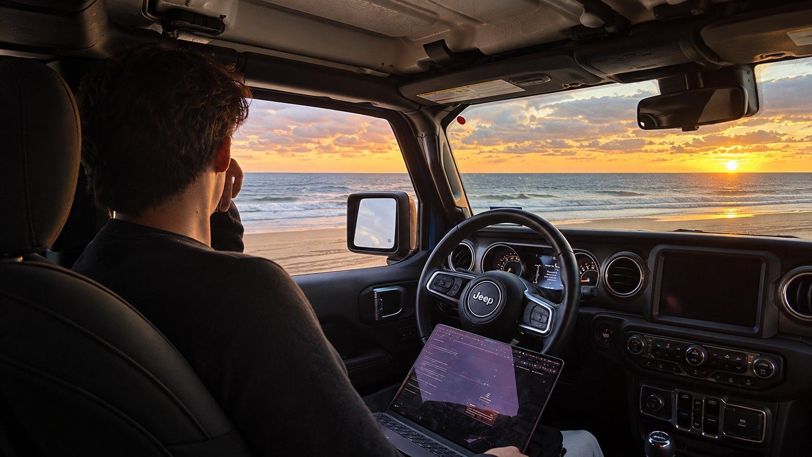 Arbeiten aus einem Jeep am Meer bei Sonnenuntergang